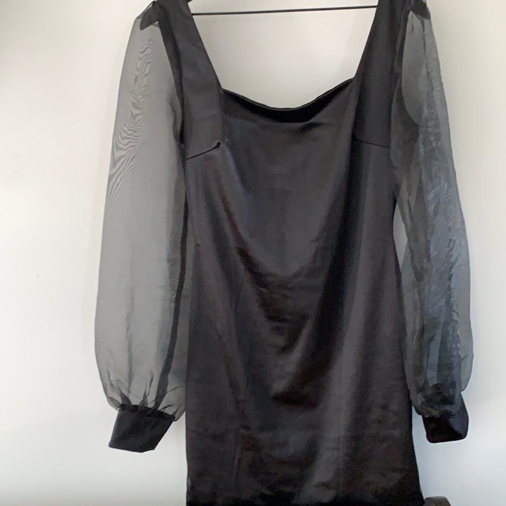 Sateen black cocktail dress with sheer sleeves. Above the knee.